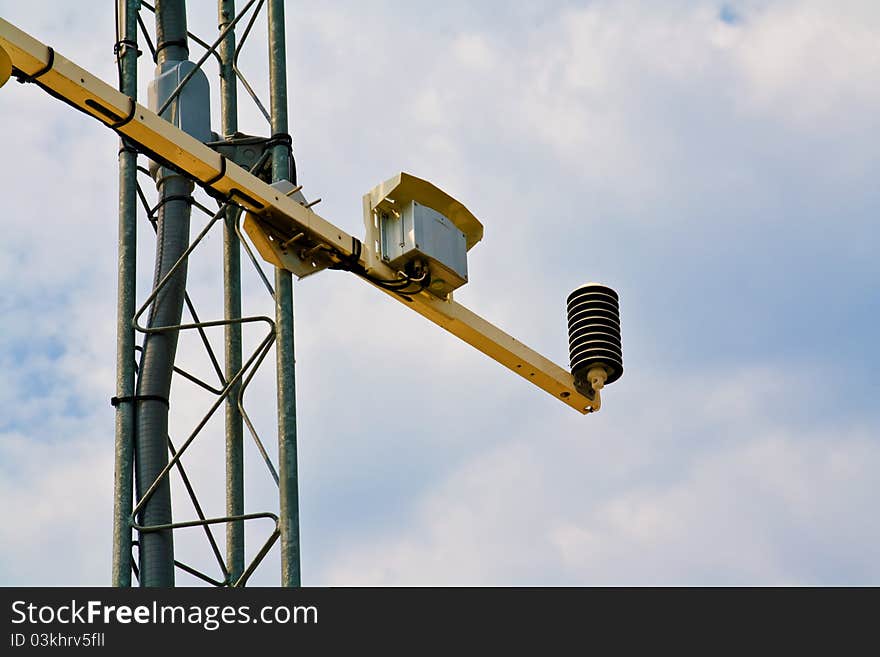 Barometer on weather station antenna under cloudy skies