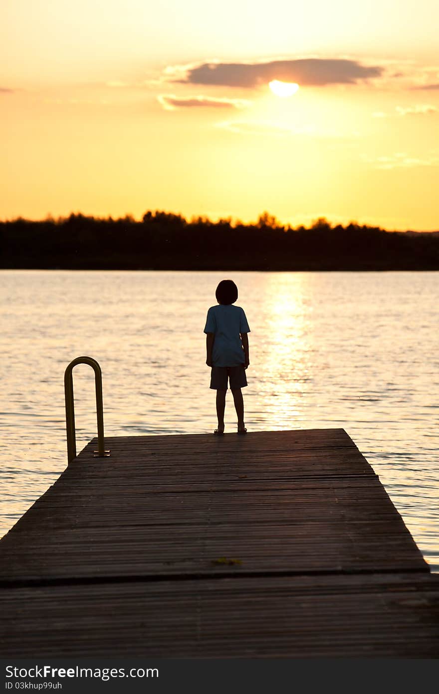 One kid standing on the bridge in the light of sunset. One kid standing on the bridge in the light of sunset.