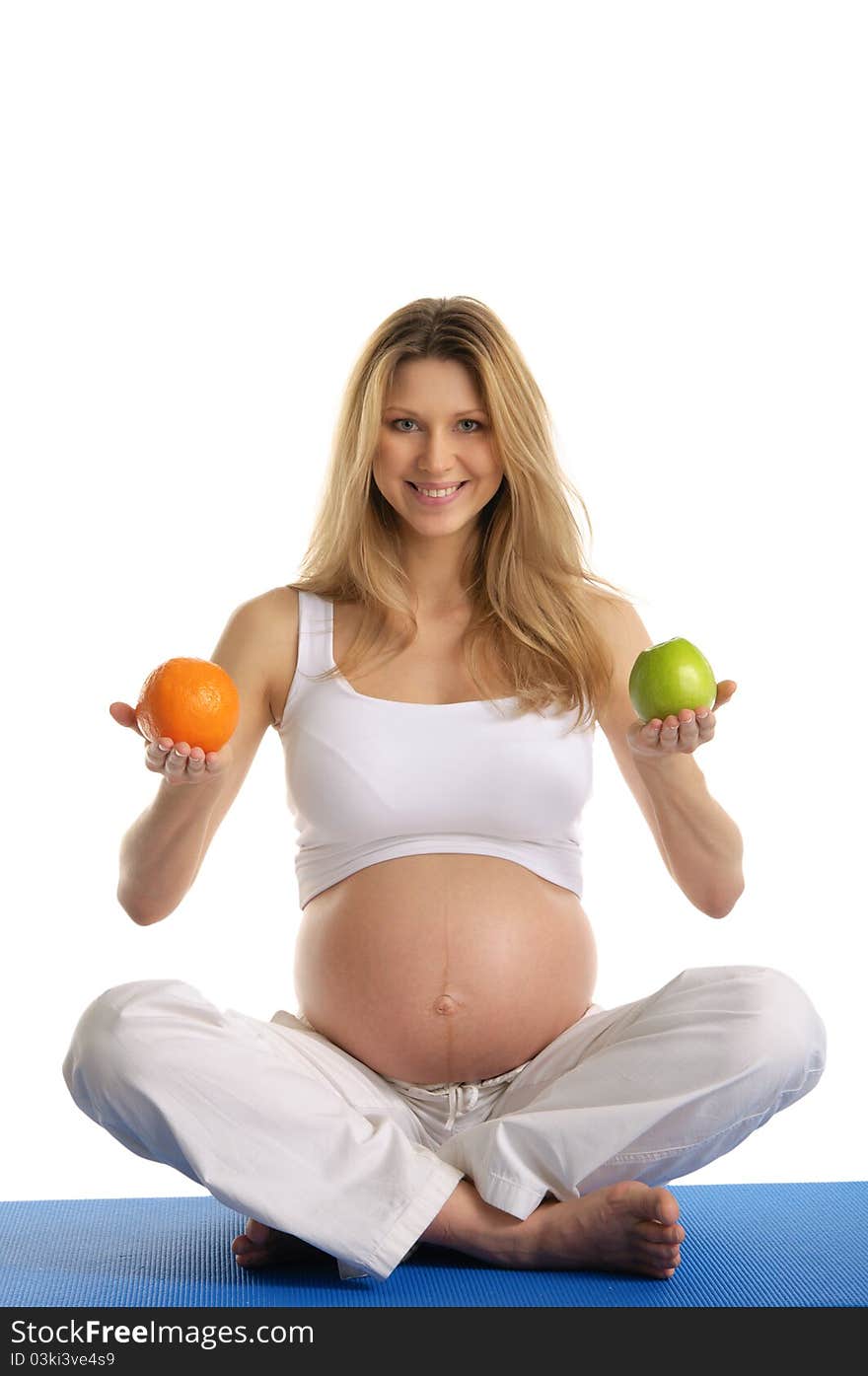 Pregnant woman practicing yoga and keeps fruit isolated on white