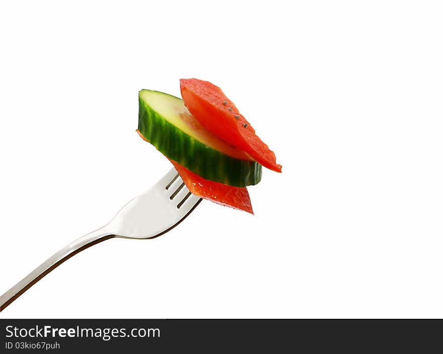 Slices of red pepper and cucumber on the fork isolated. Slices of red pepper and cucumber on the fork isolated