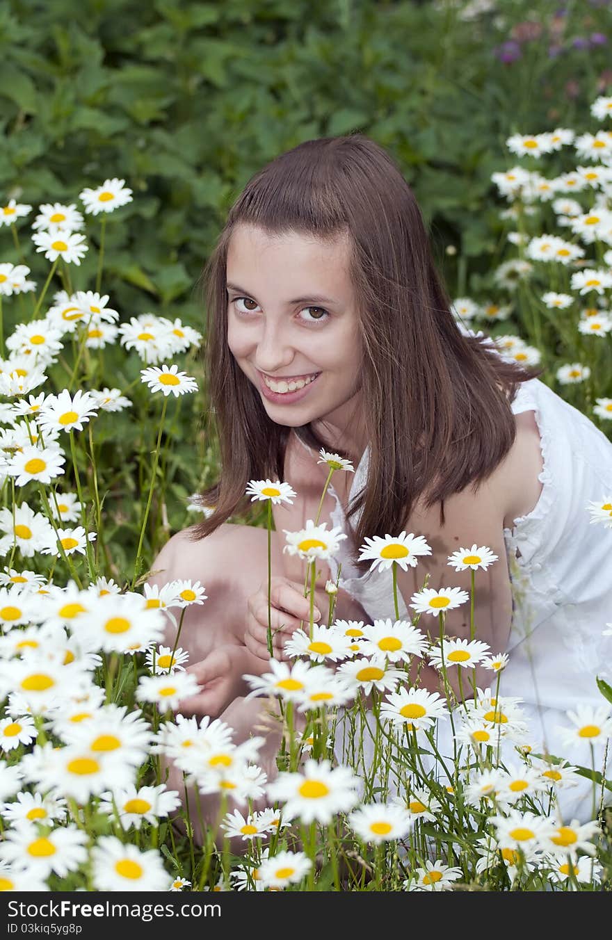 Portrait of smiling young girl sitting among daises. Portrait of smiling young girl sitting among daises