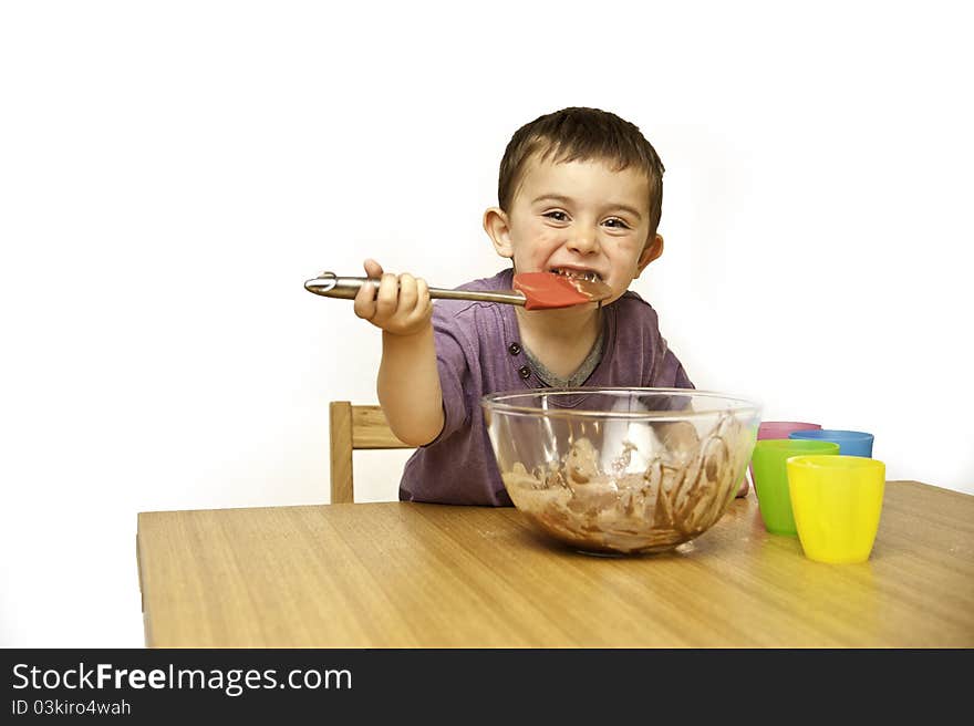 Picture of a happy young toddler mixing ingredients into a bowl isolated on a white background. Picture of a happy young toddler mixing ingredients into a bowl isolated on a white background