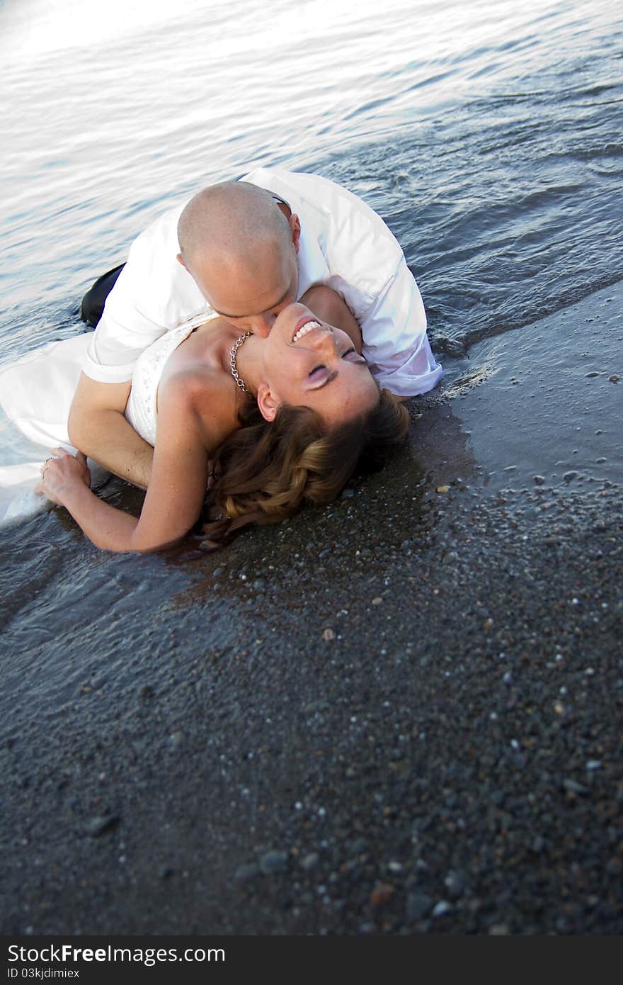 A groom kissing brides neck on beach. A groom kissing brides neck on beach