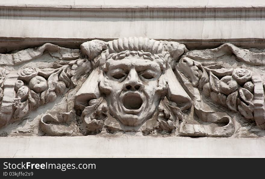 Bas-relief man's face on the wall of city street