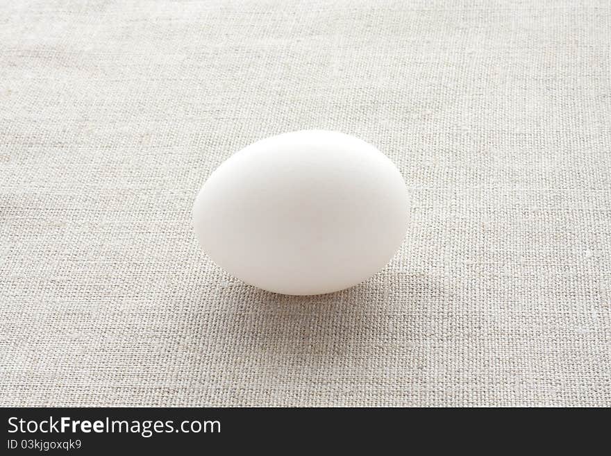 Fresh hen's egg against the background of natural fabric. Fresh hen's egg against the background of natural fabric