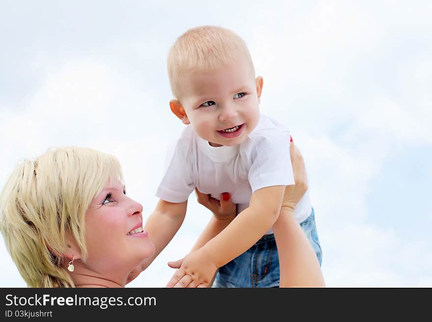 Portrait of mother holding her little baby outdoors in the summer