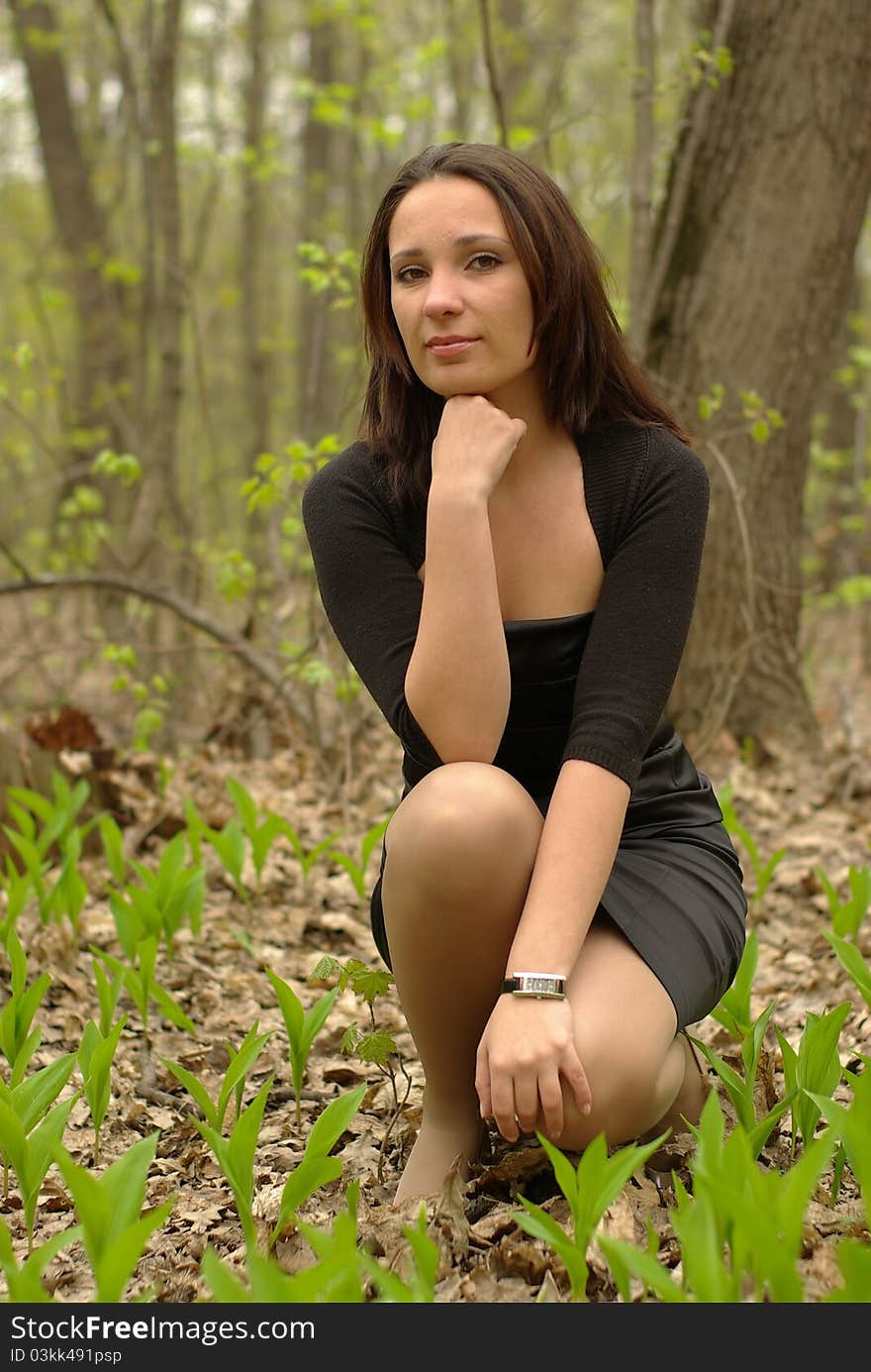 Girl in a little black dress sitting in the forest. Girl in a little black dress sitting in the forest