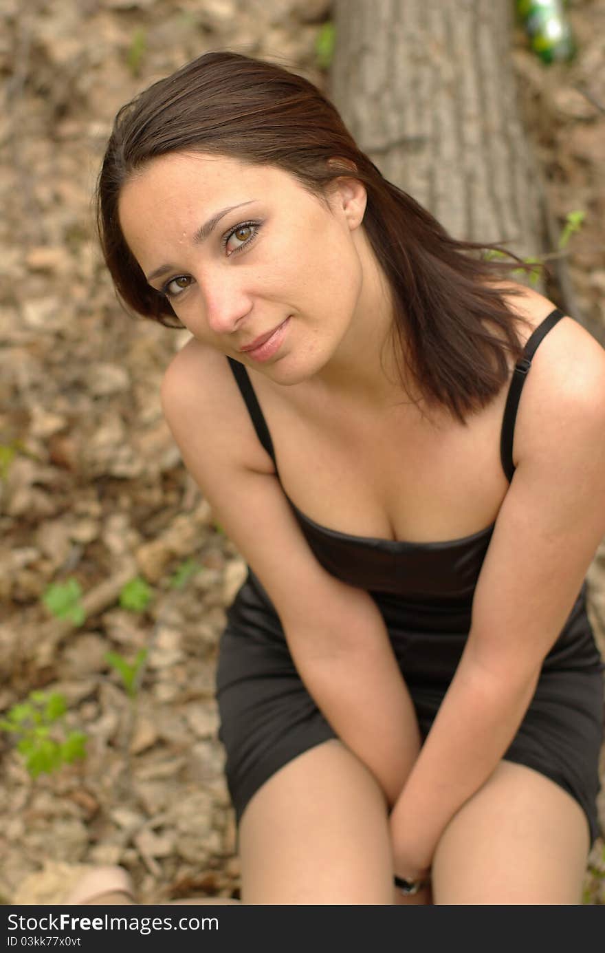 Self-conscious girl sitting on a log in the spring forest. Self-conscious girl sitting on a log in the spring forest