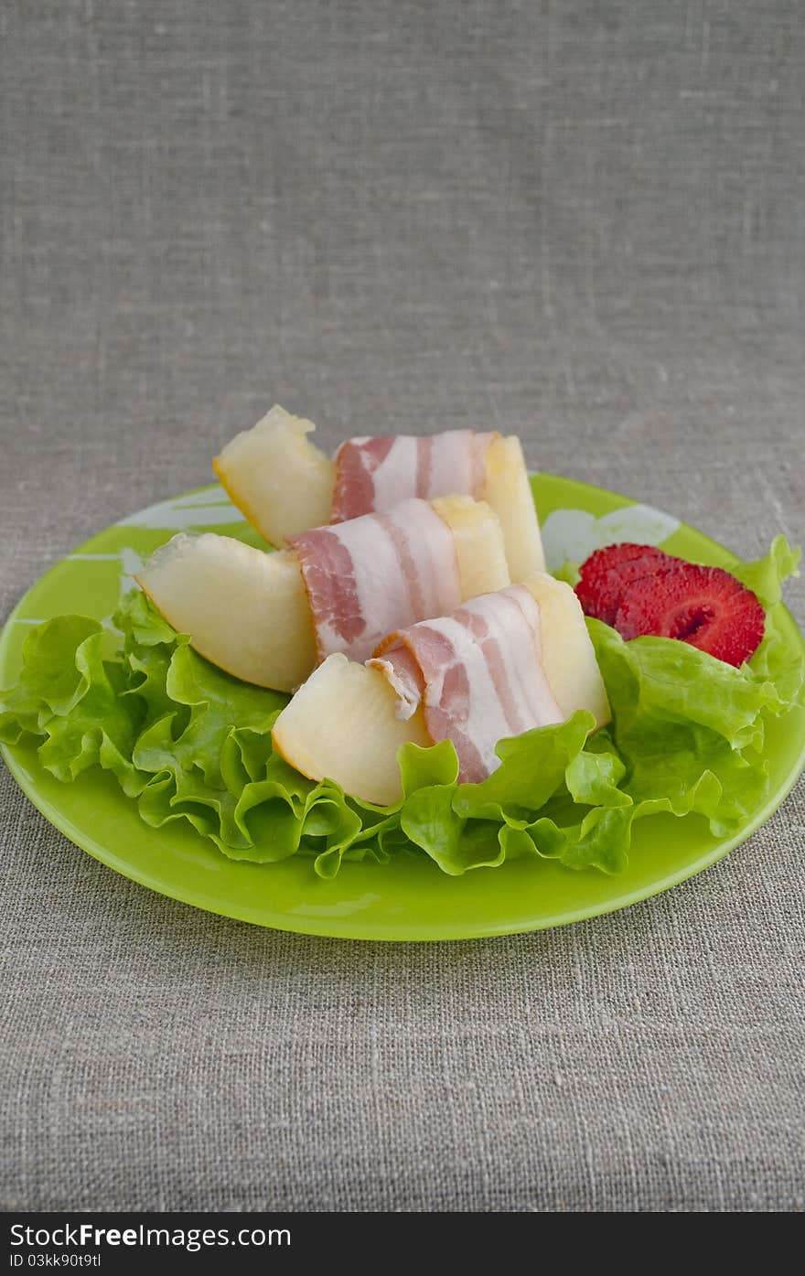 Melon with Parma ham on a green plate