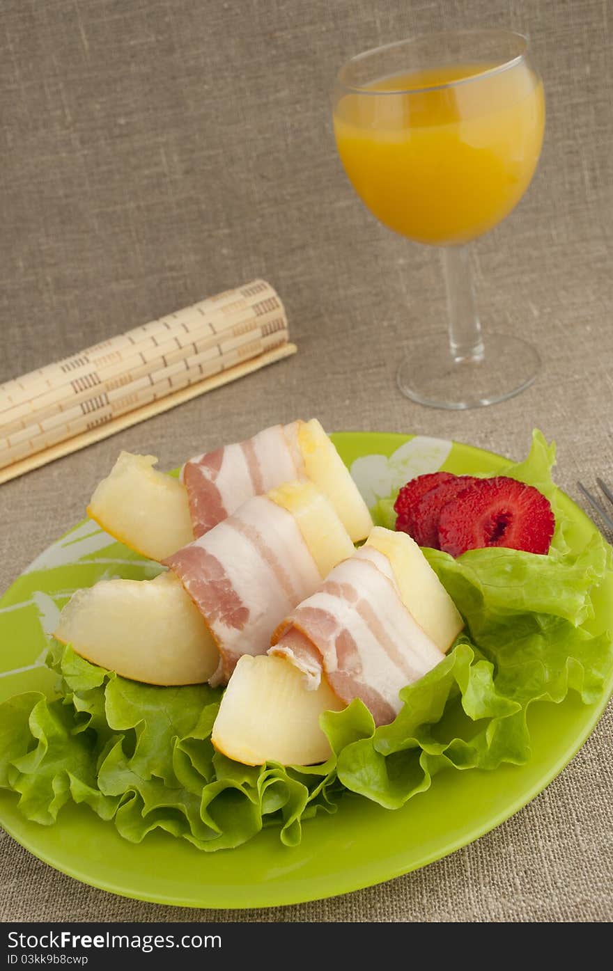 Melon with Parma ham on a green plate