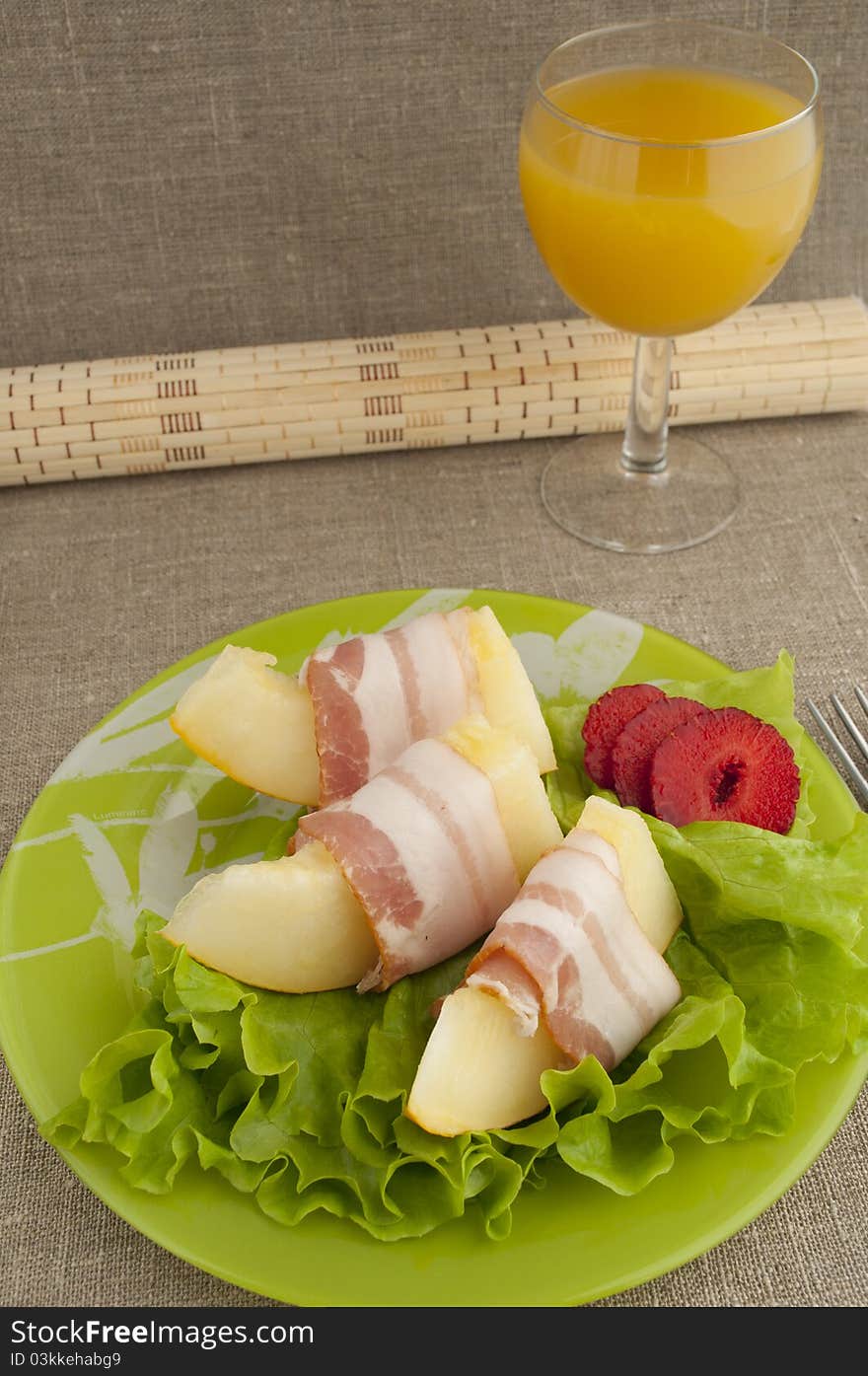 Melon with Parma ham on a green plate