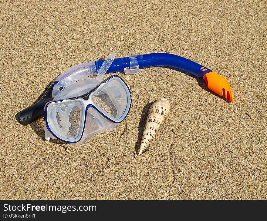 Snorkeling mask and shell on the beach