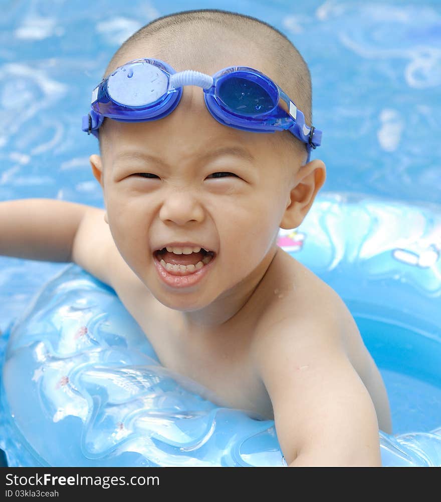 A chinese boy is in swimming, with a swim ring. A chinese boy is in swimming, with a swim ring.