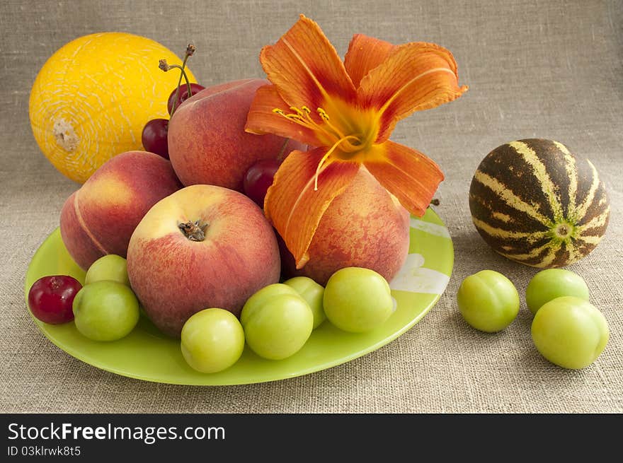 Fruit platter - melon, peaches, cherries on a background of rough cloth