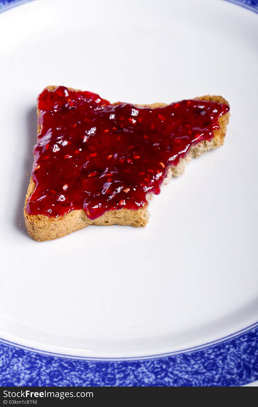 Close view of a toasted bread with berry jam spread   on a white background. Close view of a toasted bread with berry jam spread   on a white background.