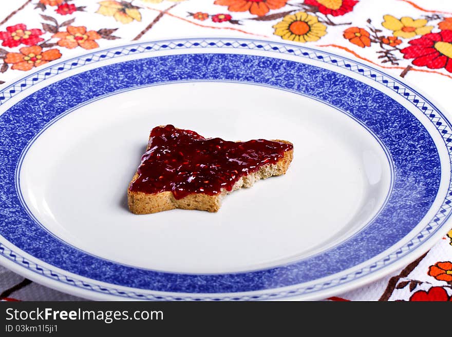 Close view of a toasted bread with berry jam spread on a white background. Close view of a toasted bread with berry jam spread on a white background.