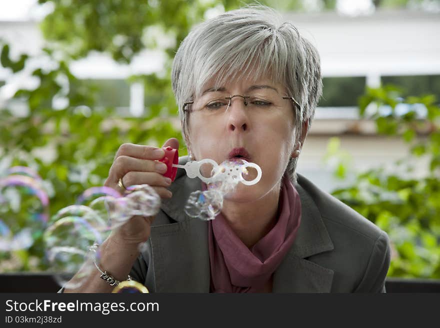 Woman, 50 +, blowing soap bubbles. Woman, 50 +, blowing soap bubbles