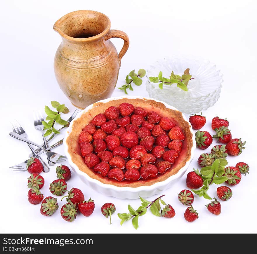 Strawberry Tart, plates, a pot, forks, strawberries and mint twigs on a white background