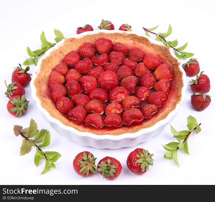 Strawberry Tart decorated with strawberries and mint twigs on a white background