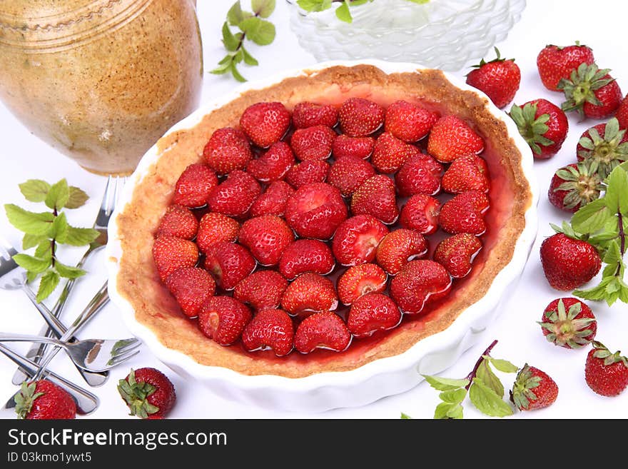 Strawberry Tart, plates, a pot, forks, strawberries and mint twigs on a white background