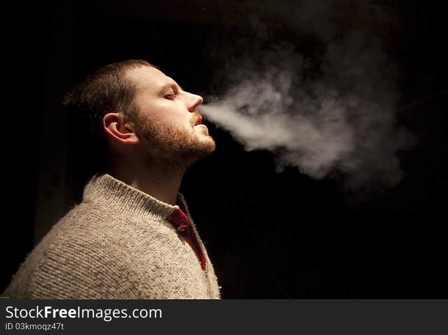 A man smoking and exhaling out of his nose.