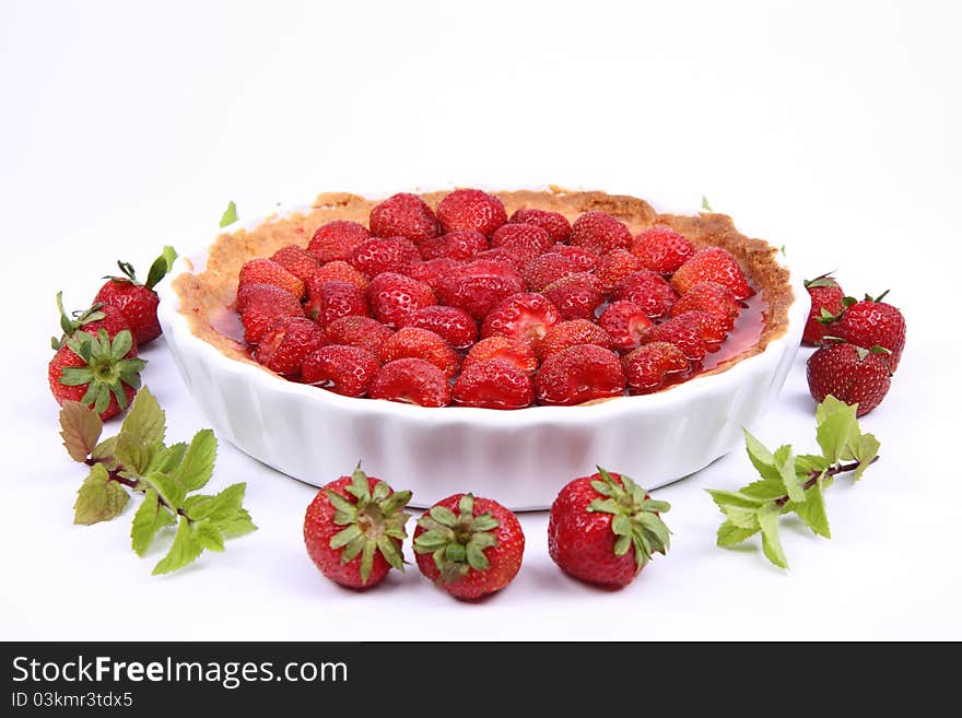 Strawberry Tart decorated with strawberries and mint twigs on a white background