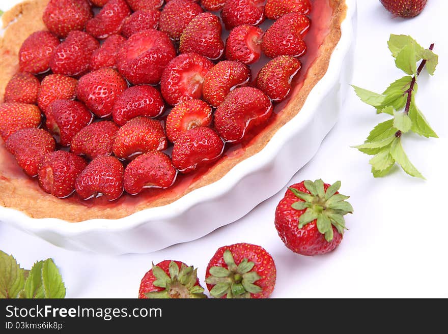 Strawberry Tart decorated with strawberries and mint twigs on a white background