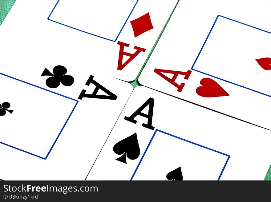 Close up view of a set of four aces spread on a green cloth table.