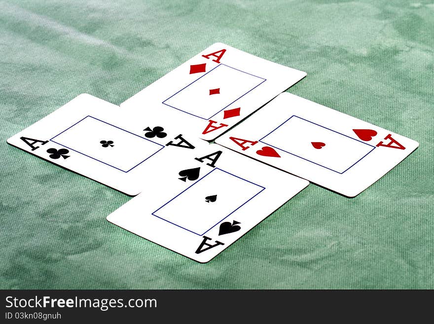 Close up view of a set of four aces spread on a green cloth table.