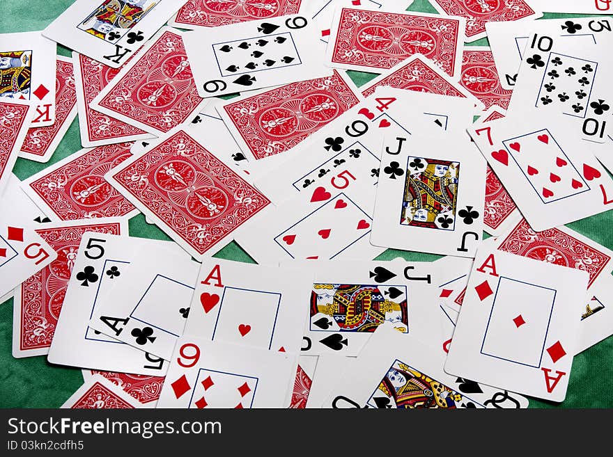 Close up view of a bunch of playing cards spread on a green cloth table. Close up view of a bunch of playing cards spread on a green cloth table.