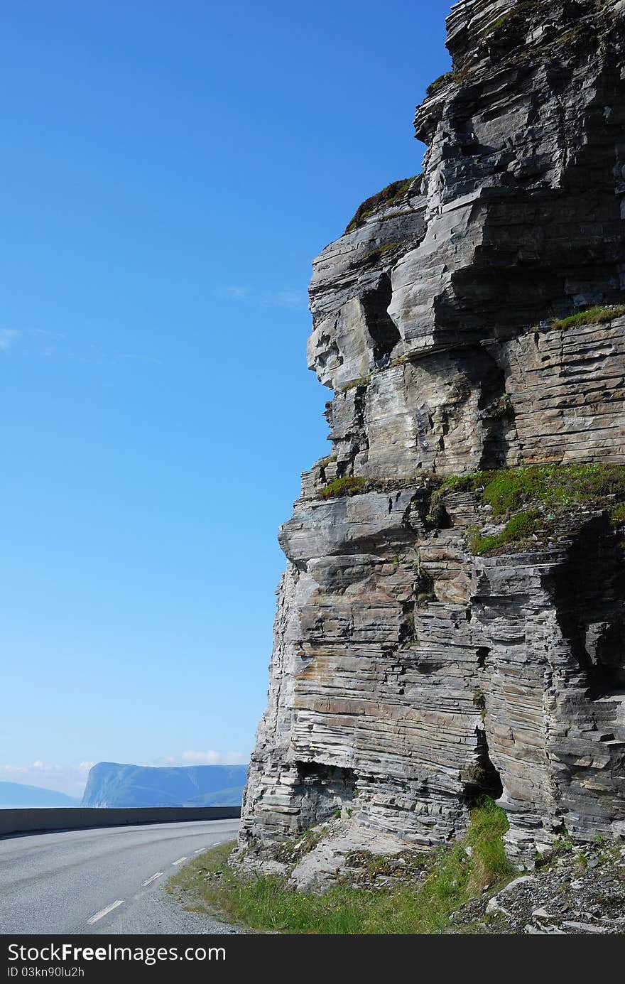 Vertical cliff and serpentine road.