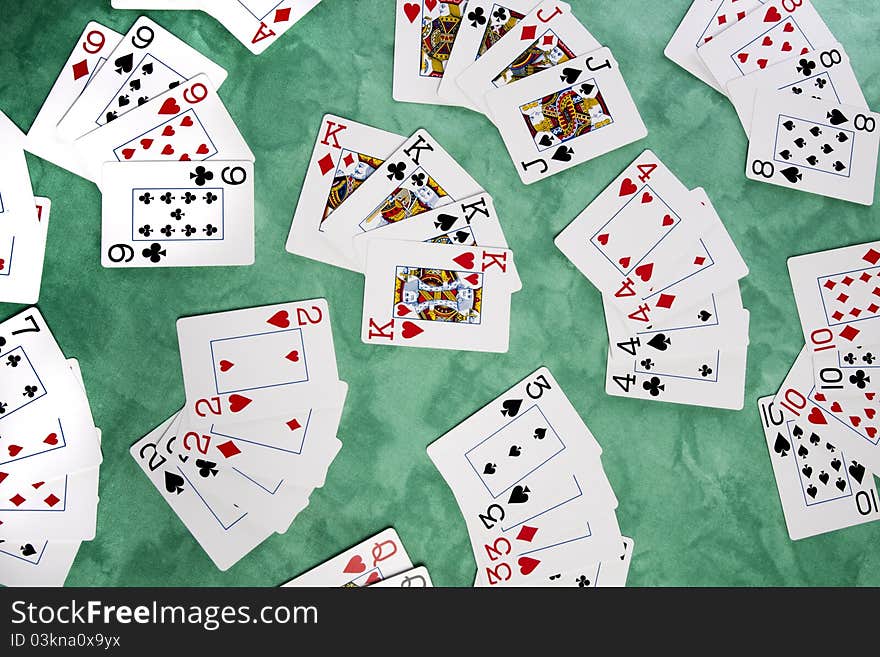 Close up view of a bunch cards spread on a green cloth table. Close up view of a bunch cards spread on a green cloth table.