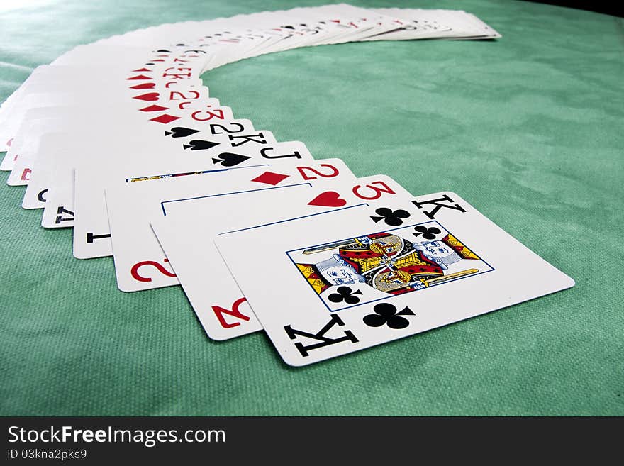 Close up view of a bunch cards spread on a green cloth table. Close up view of a bunch cards spread on a green cloth table.