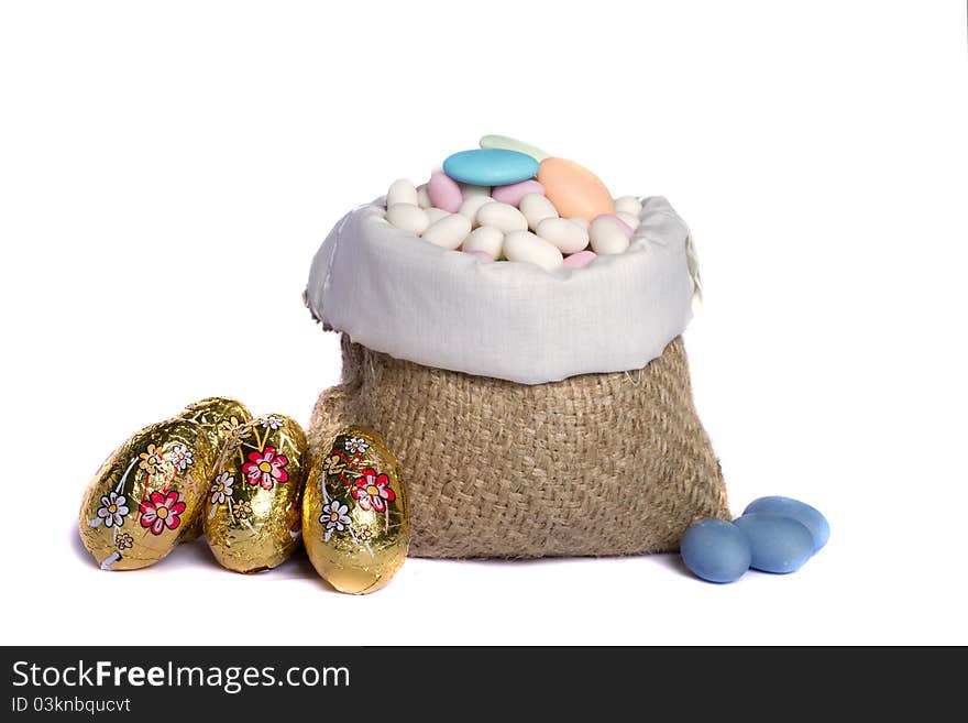 Close up view of sweet almonds and chocolate eggs inside a sack isolated on a white background. Close up view of sweet almonds and chocolate eggs inside a sack isolated on a white background.