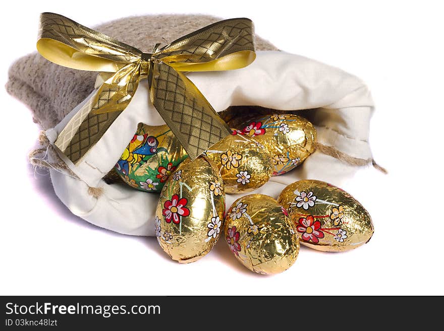 Close up view of sweet golden eggs inside a sack isolated on a white background.