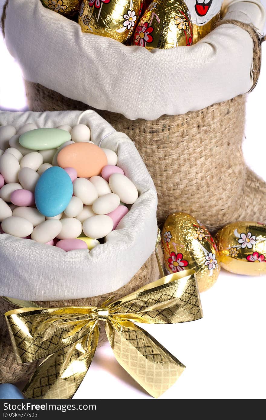 Close up view of sweet almonds and chocolate eggs inside a sack isolated on a white background. Close up view of sweet almonds and chocolate eggs inside a sack isolated on a white background.