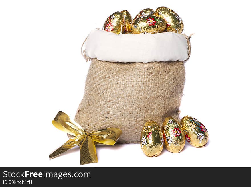 Close up view of sweet golden eggs inside a sack isolated on a white background.