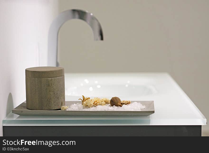 Bath salt and dried flowers on washbasin in design bathroom