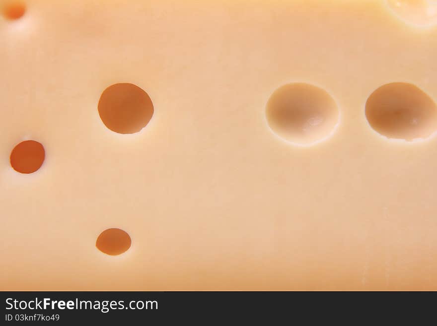 Cut cheese with big round holes close up