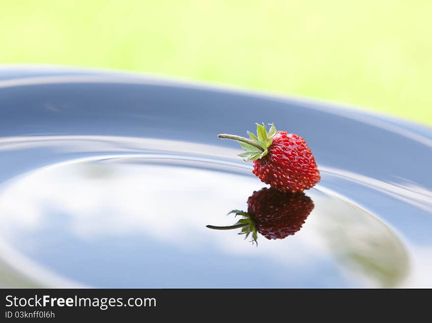 Single strawberry on black plate. Single strawberry on black plate