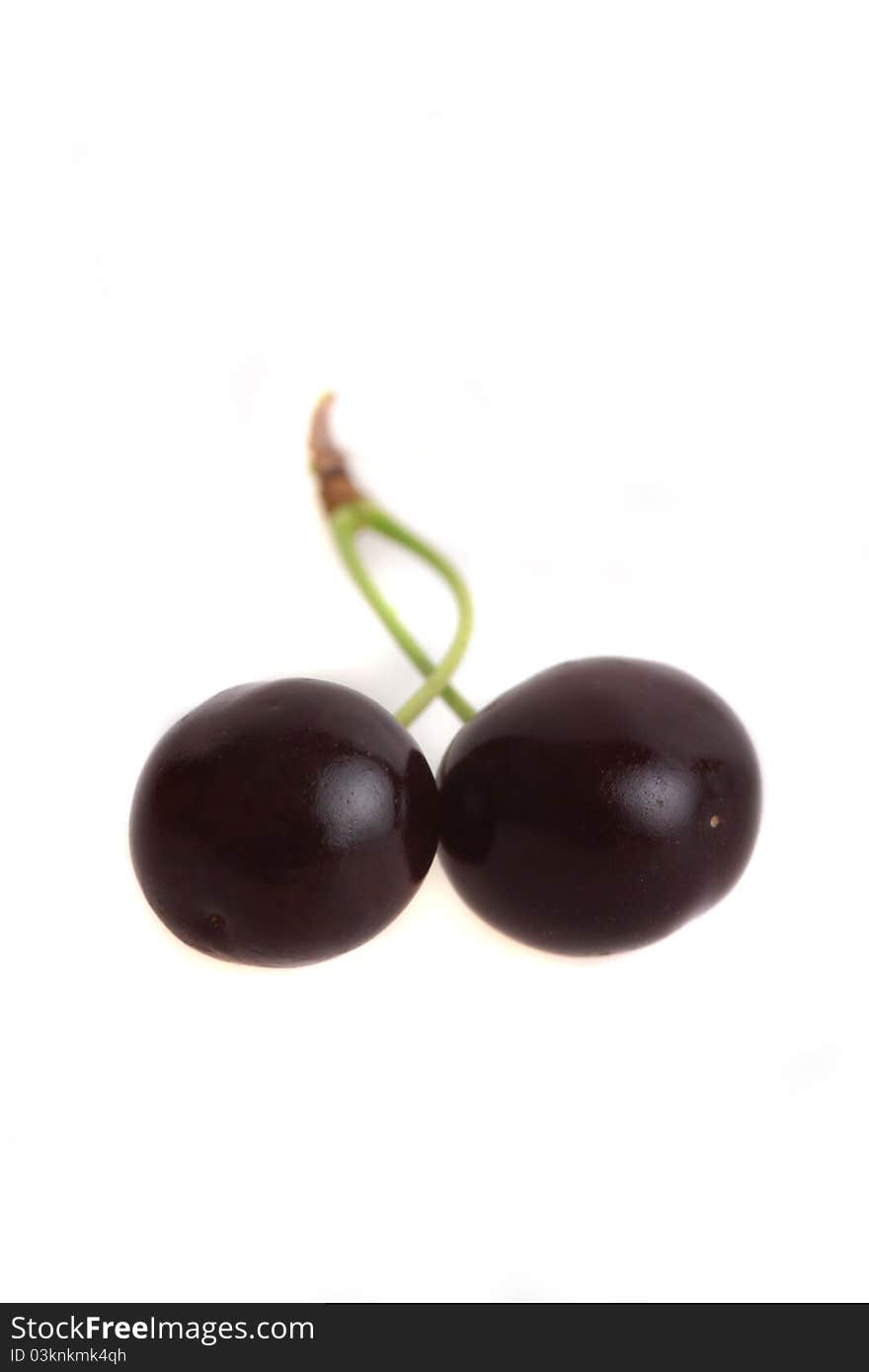 Two black cherries on a green stipe