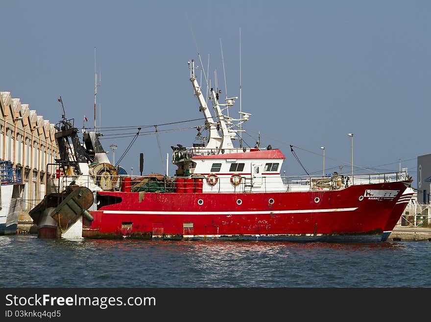 View of a red fishing boat anchored on the docks.