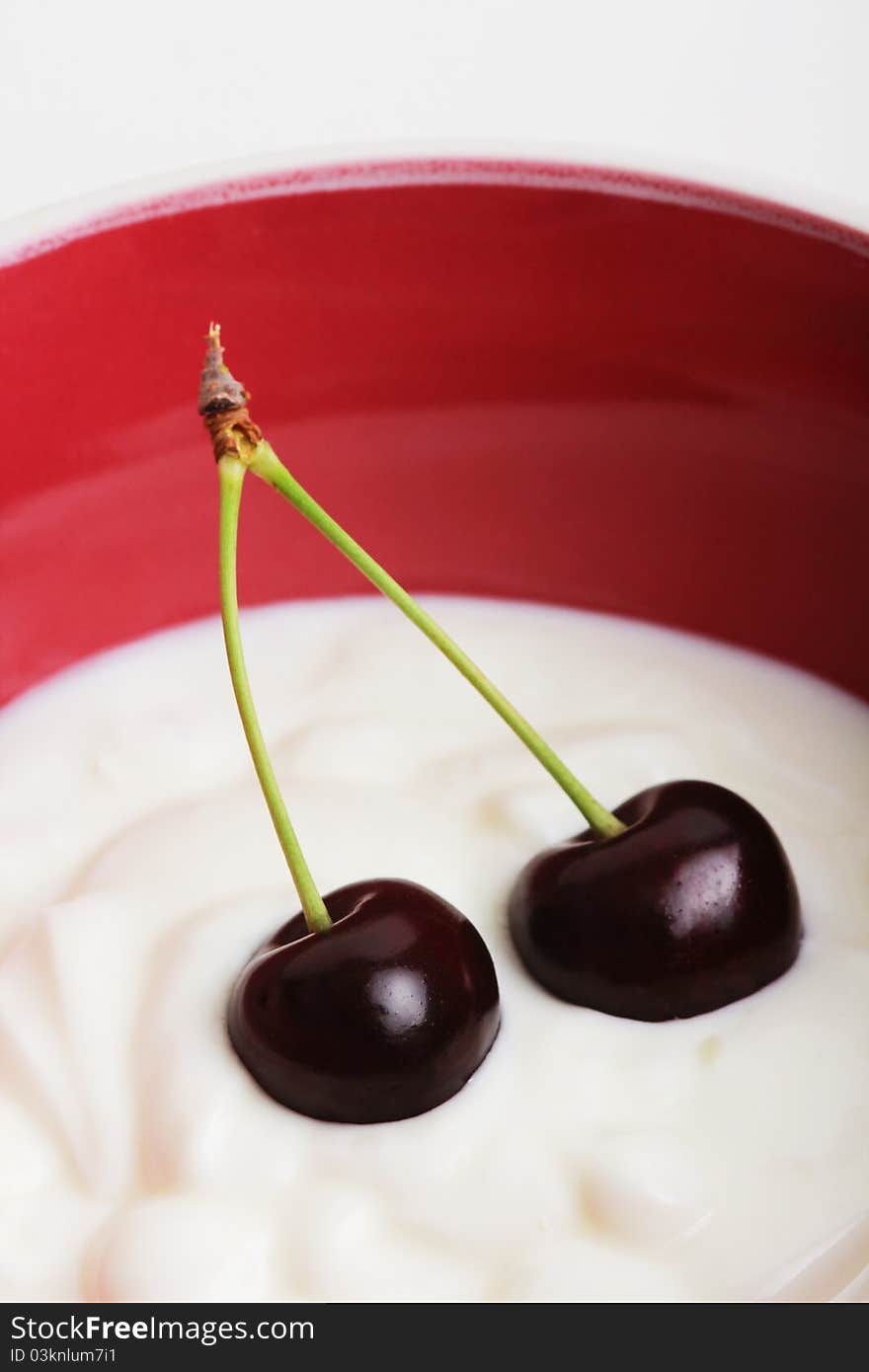 Two black cherries in a bowl with yogurt. Two black cherries in a bowl with yogurt