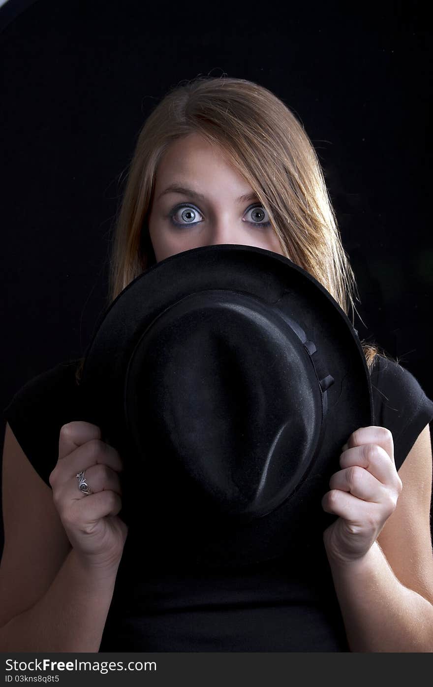 A blond girl looking over the black hat. A blond girl looking over the black hat