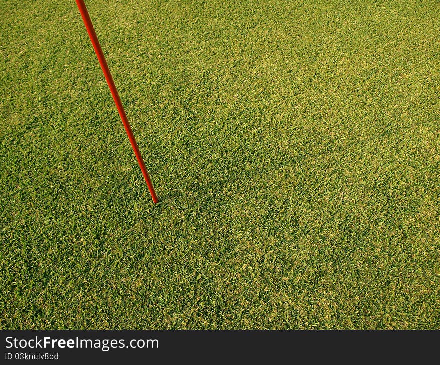 Red marking flag pole on fresh green grass field. Red marking flag pole on fresh green grass field