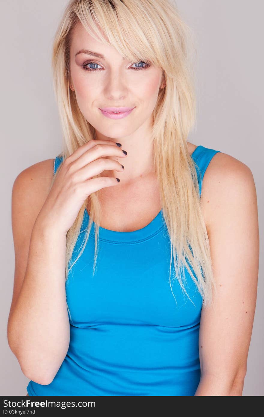 Close up portrait  of a attractive young blond woman wearing a blue top. Close up portrait  of a attractive young blond woman wearing a blue top.