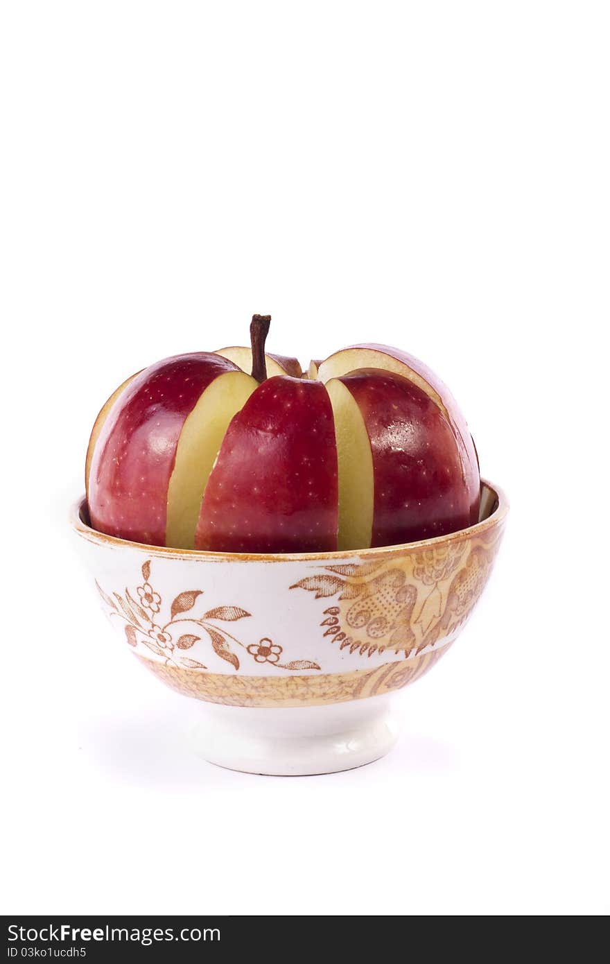 Close up view of a single red apple sliced inside a bowl isolated on a white background.