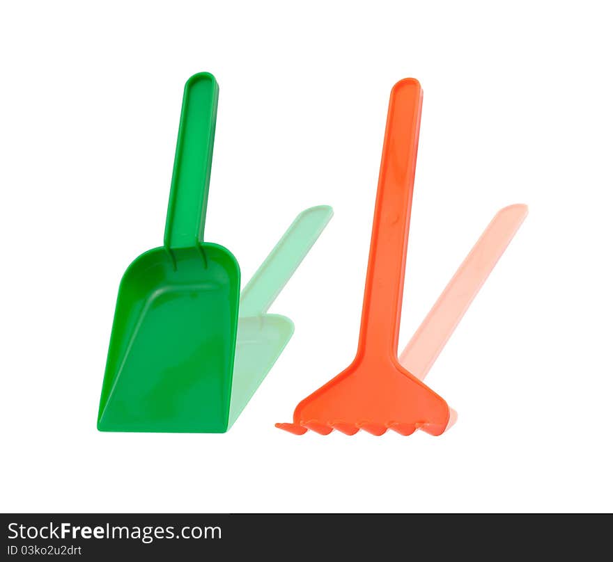 Red rake and green shovel on isolated background. Red rake and green shovel on isolated background