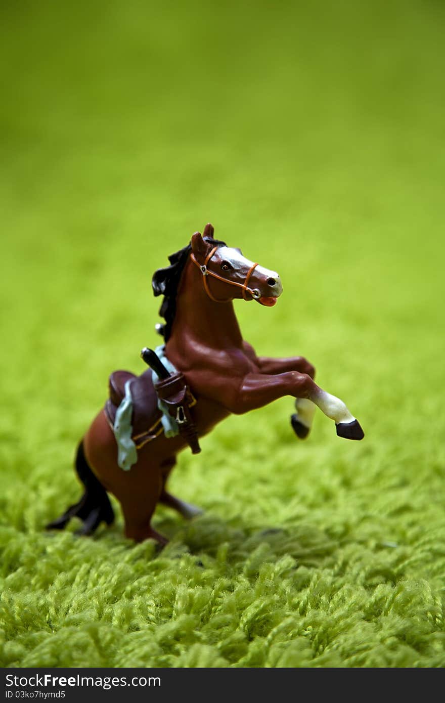 Miniature toy horse in running posture on a carpet like grass. Miniature toy horse in running posture on a carpet like grass