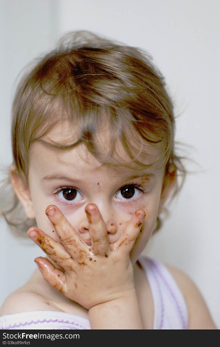 Little girl after eating chocolate with fingers on face and focus on eyes. Little girl after eating chocolate with fingers on face and focus on eyes